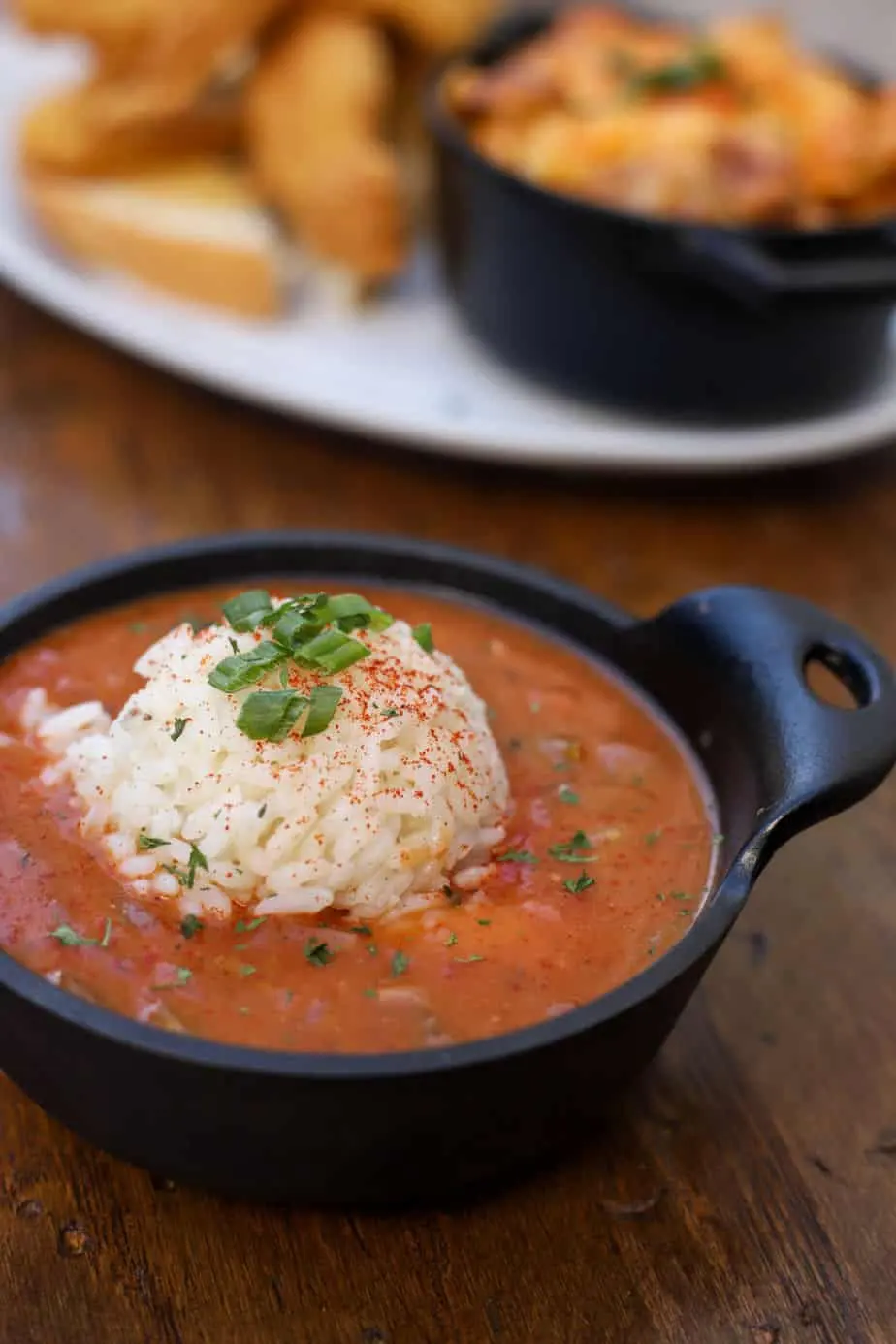A cast iron bowl of soup with a scoop of rice