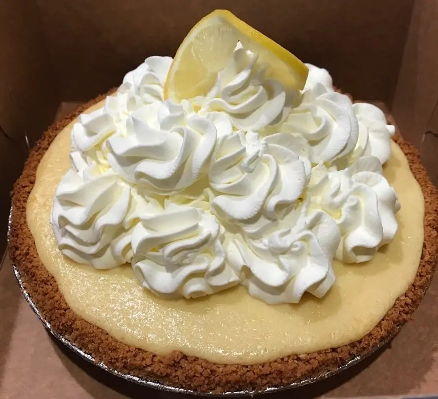 Lemon pie topped with whipped cream and a lemon slice